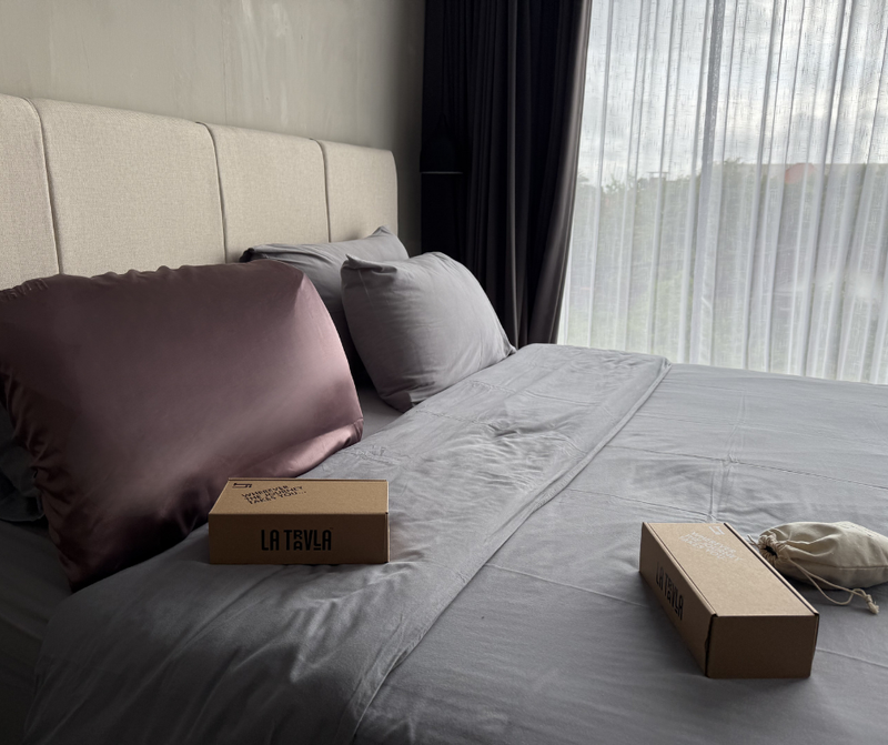 SOJOURN PillowWrap on an airbnb bed with packaging and organic travel pouch.