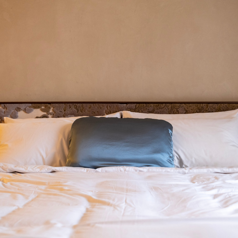 Bed with white pillows and a LATRAVLA VISTA PillowWrap in hotel.