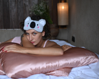 Woman wearing a koala eye mask on a bed with the latravla  pillowwrap - mulberry silk and silver nanoparticle travel pillowcase.